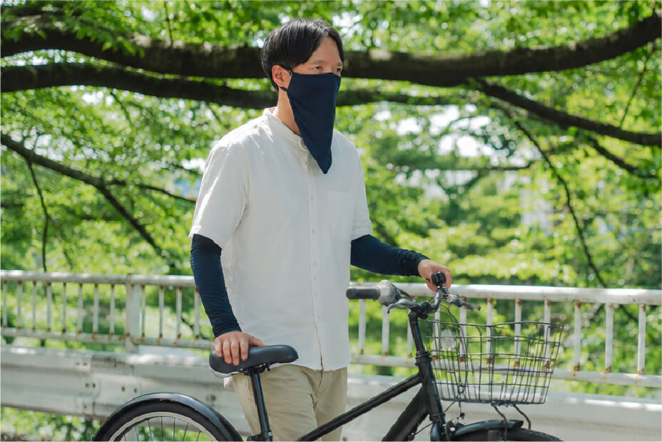 自転車のそばで冷感シルクアームカバーとフェイスカバーを着用した男性スタッフ